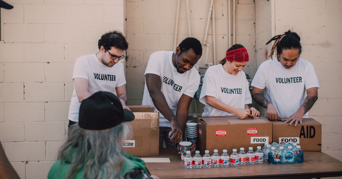 Group of volunteers organizing and distributing aid packages and bottled water outdoors.